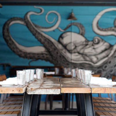 set table with glasses and mural of an octopus on restaurant wall